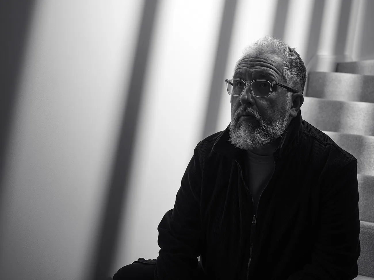 sat on the stairs in my house with a strong shadows cast against the wall