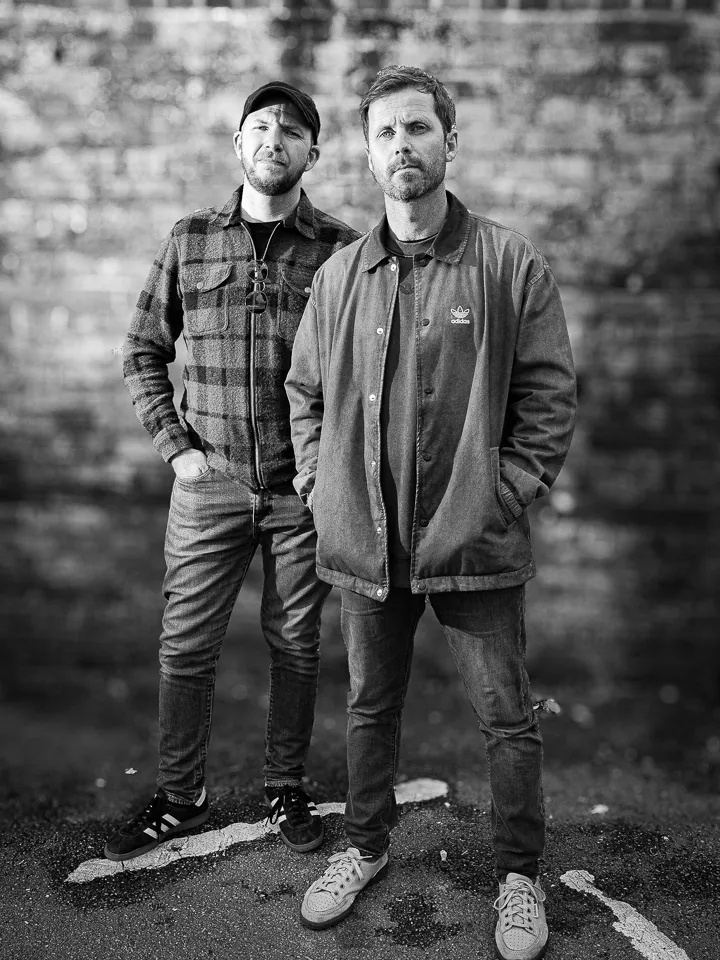 black and white portrait of Tommy and Darren by a brick wall