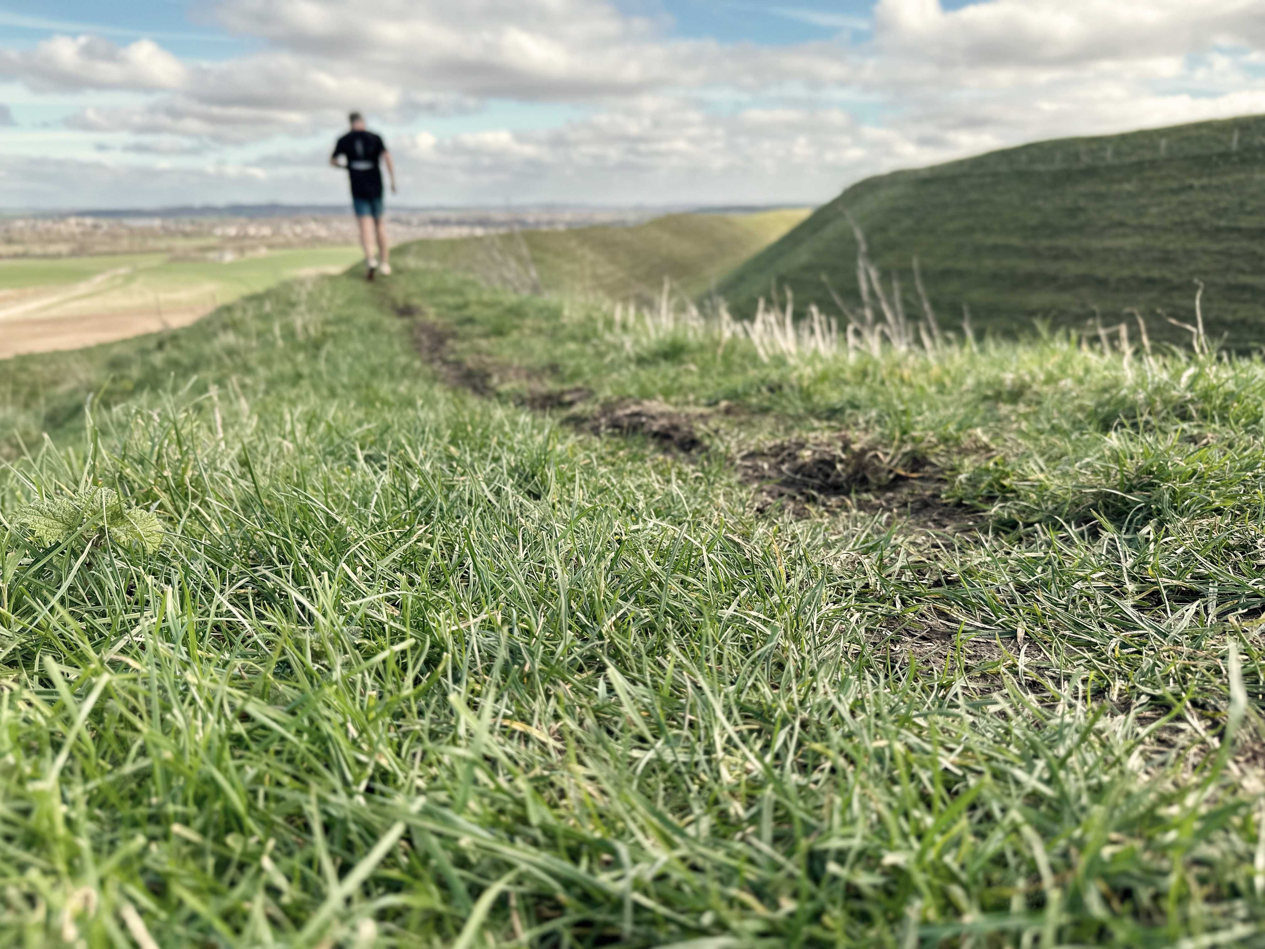Trail running Stu stumbles into the distance on the ramparts of maiden castle in dorset!